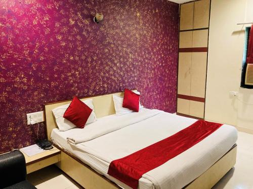 a bedroom with a large bed with red pillows at Hotel Jagdish in Raipur