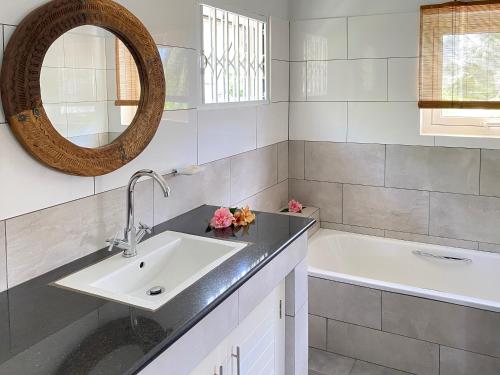 a bathroom with a sink and a tub and a mirror at Chalets Bougainville in Takamaka