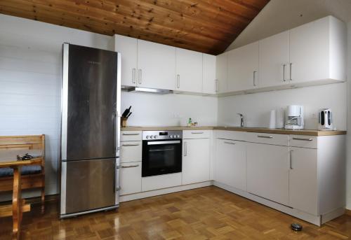 cocina con armarios blancos y nevera de acero inoxidable en Ferienwohnung Tannenblick - 3 Schlafzimmer, Feldberg-Falkau, en Hinterfalkau