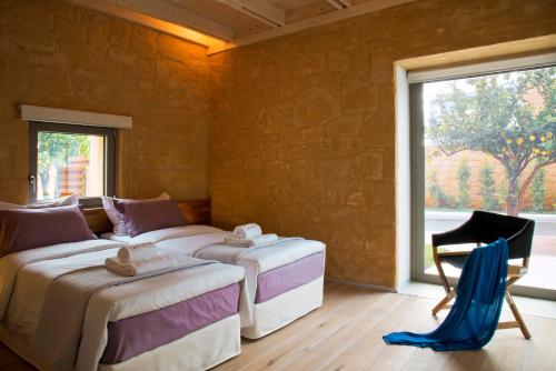 a bedroom with two beds and a chair and a window at Conte Marino Villas in Maleme