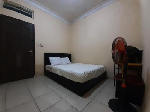 una piccola camera con letto e sedia di SPOT ON 93326 Pondok Anie Syariah a Pekanbaru