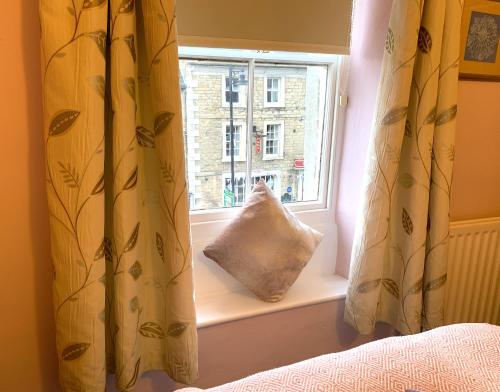 a window with a pillow sitting in a window sill at Spacious Georgian Apartment, Central Barnard Castle. in Barnard Castle