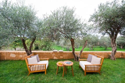 three chairs and a table in a yard with trees at Conte Marino Villas in Maleme