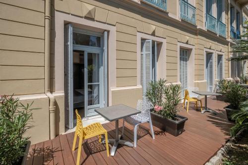 a patio with tables and chairs on a building at Hôtel Miléade L'Orangeraie - Menton in Menton