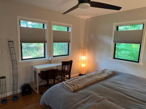 a bedroom with a bed and a desk and windows at Schoolhouse No. 11 * Hudson Valley Upstate Getaway in Stone Ridge