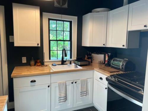 a kitchen with white cabinets and a sink and a window at Schoolhouse No. 11 * Hudson Valley Upstate Getaway in Stone Ridge