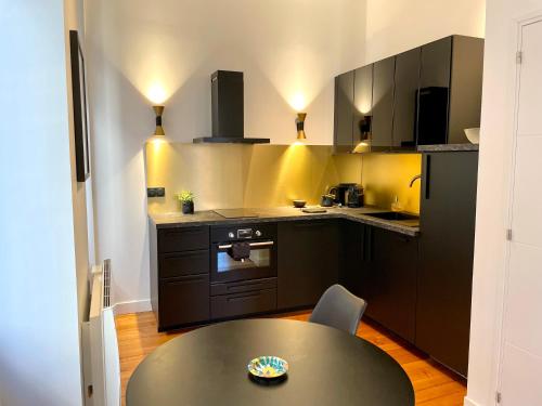 une cuisine avec des armoires noires et une table. dans l'établissement Merveilleux T2 de Standing à 90m de la Garonne, à Toulouse