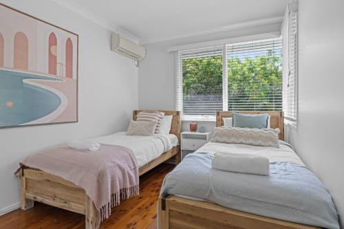 two beds in a room with a window at Bonus Studio Space in Budgewoi