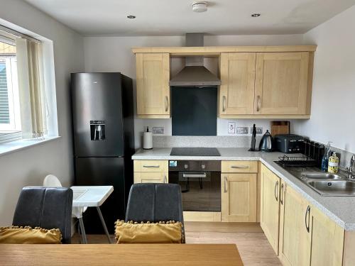 une cuisine avec des armoires en bois et un réfrigérateur noir dans l'établissement Stafford 2 Bedroom Apartment in Prime Location with Secure Parking, à Stafford