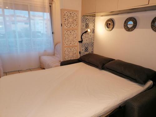 1 dormitorio con cama, ventana y sofá en 028 Cap City B25, en Cap d'Agde