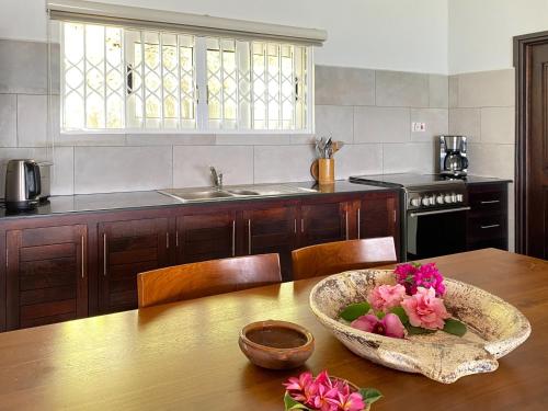 eine Küche mit einem Tisch und einer Schüssel Blumen darauf in der Unterkunft Chalets Bougainville in Takamaka