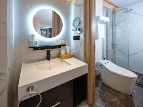 a bathroom with a sink and a mirror and a tub at Moon River View Hotel in Fenghuang
