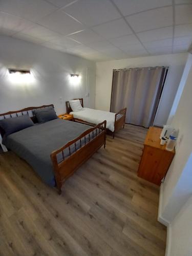 1 dormitorio con 2 camas y suelo de madera en Chambre d'hôtels, en Champeix