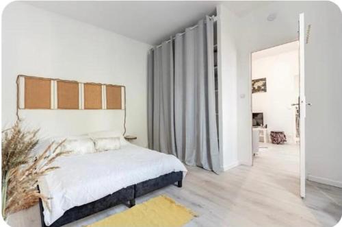een witte slaapkamer met een bed en een groot raam bij Maison cosy Paris Orly jardin privée in Vitry-sur-Seine