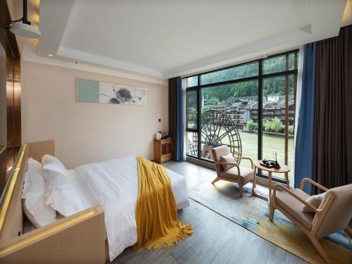 a bedroom with a bed and a large window at Moon River View Hotel in Fenghuang County