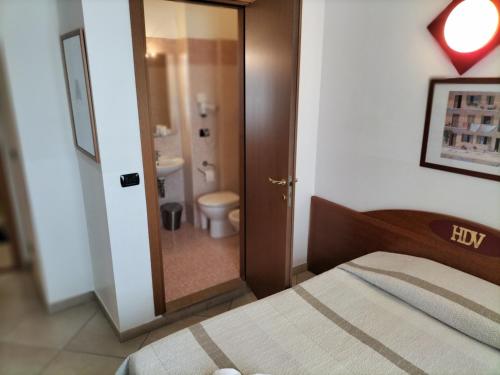 a bedroom with a bed and a bathroom with a toilet at Hotel Della Volta in Brescia
