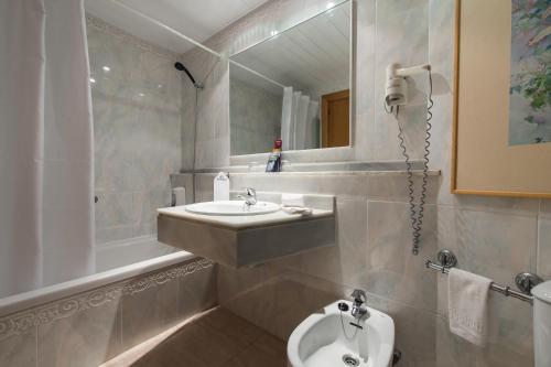 uma casa de banho com um lavatório, um WC e um espelho. em Exagon Park em Can Picafort