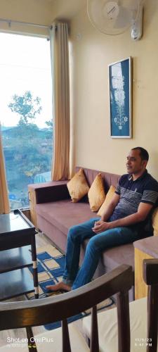 a man sitting on a couch in a living room at Hotel Mahishmati Palace in Maheshwar