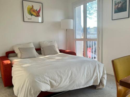 une chambre avec un lit blanc et une fenêtre dans l'établissement Nîmes centre Superbe studio, à Nîmes