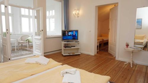 a room with a bed and a television in it at Villa Emanuel mit Meerblick in Ahlbeck