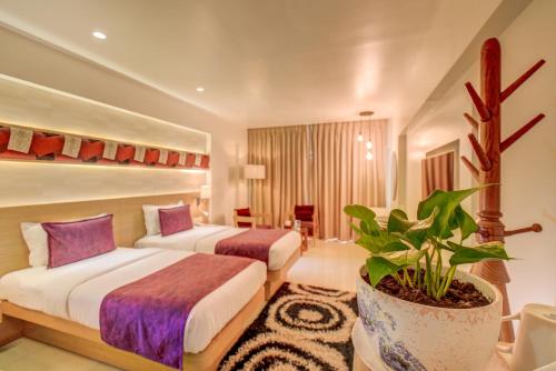 a hotel room with two beds and a potted plant at The SSK Solitaire Hotel & Banquets in Nashik