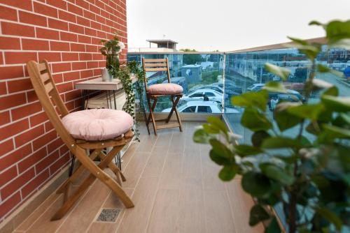 a balcony with two chairs and a table on a brick wall at Urban Bliss - Contemporary Elegance in Modern Living Spaces in Voluntari