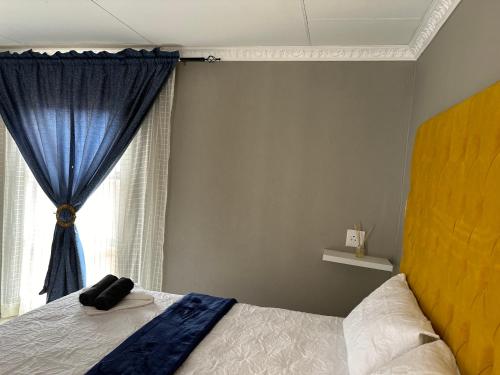 a bedroom with a bed with a blue curtain and a window at Dee Park Entertainment Centre in Thohoyandou