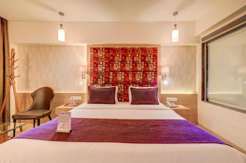 a hotel room with a large bed and a red wall at The SSK Solitaire Hotel & Banquets in Nashik