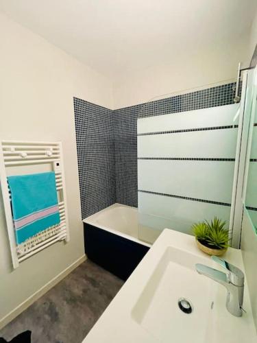 une salle de bain blanche avec un lavabo et une fenêtre dans l'établissement Un nid dans les pins La Baule, à La Baule