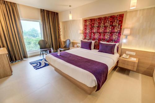 a hotel room with a large bed and a window at The SSK Solitaire Hotel & Banquets in Nashik