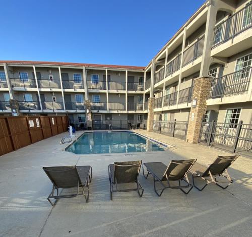 un grand immeuble avec une piscine et des chaises dans l'établissement Wingate by Wyndham Galveston East Beach, à Galveston