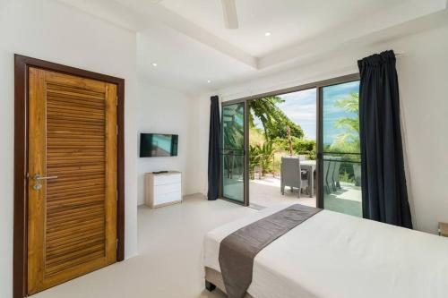 a bedroom with a bed and a large window at Villa 7 chambres vue mer in Ban Khlong Mae Nam