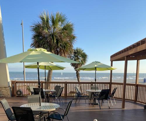 a patio with tables and umbrellas and the beach at Wingate by Wyndham Galveston Beachfront at the Seawall in Galveston