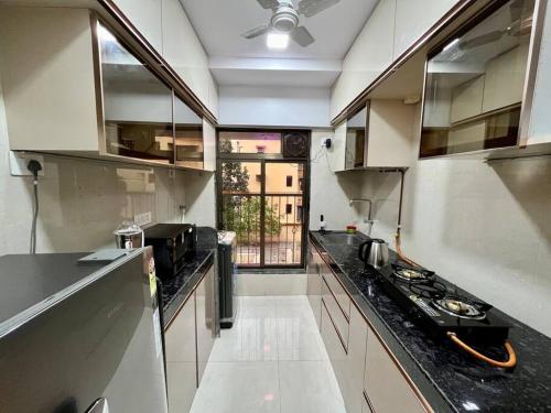 a kitchen with white cabinets and a black counter top at La Alba 1 BHK Serviced Apartment in Mumbai