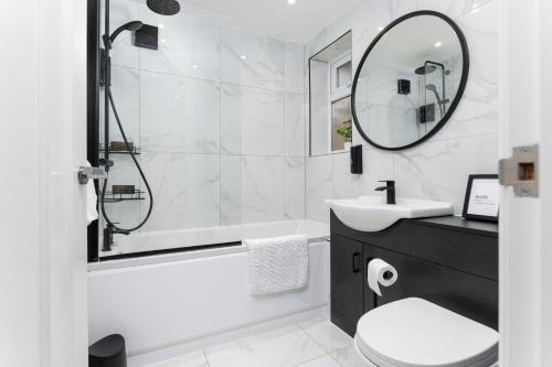 a bathroom with a tub and a sink and a mirror at Flatzy - Stunning Home by Lark Lane with Pool Table in Liverpool