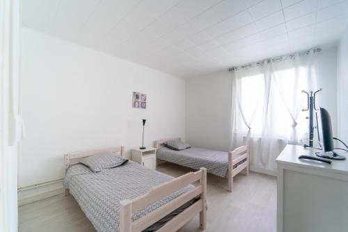 une chambre avec deux lits, un bureau et une télévision dans l'établissement Florévasion - Appt pour 5, à Bobigny