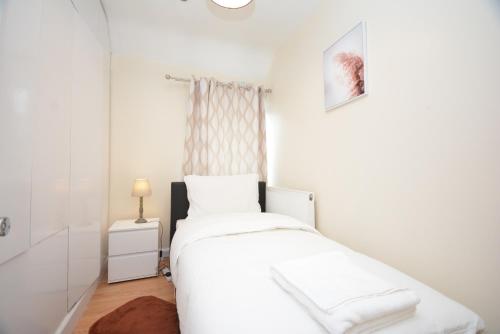 a white bedroom with a bed and a window at Lovely 3 Bedroom House Dagenham in Dagenham