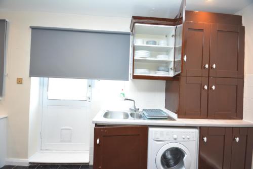 a kitchen with a sink and a washing machine at Lovely 3 Bedroom House Dagenham in Dagenham