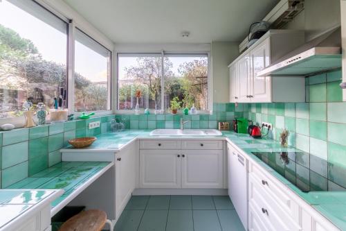 a kitchen with white cabinets and green tiles at Le Clos Lamouroux - Grande maison pour 12 in Agen