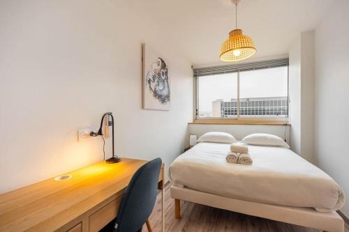 1 dormitorio con 1 cama y escritorio con 2 zapatillas en Le Prouvé * Parking Privé Inclus en Nancy