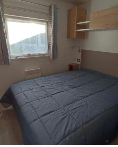 une chambre avec un lit bleu et une fenêtre dans l'établissement Les dunes de contis, à Saint-Julien-en-Born