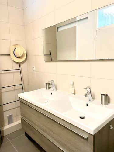 une salle de bain avec un lavabo blanc et un miroir dans l'établissement L'Hallali à la Baule centre, à La Baule