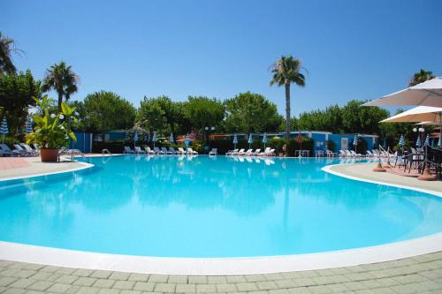 a large swimming pool with chairs and palm trees at Villaggio Welcome Riviera d'Abruzzo in Tortoreto Lido