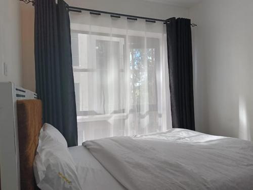 a bedroom with a window with black and white curtains at legatus cozy studios 1a in Ongata Rongai 