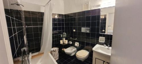a black tiled bathroom with a toilet and a sink at Cava di Volpe , Case Del Golf Pevero, Costa Smeralda in Abbiadori