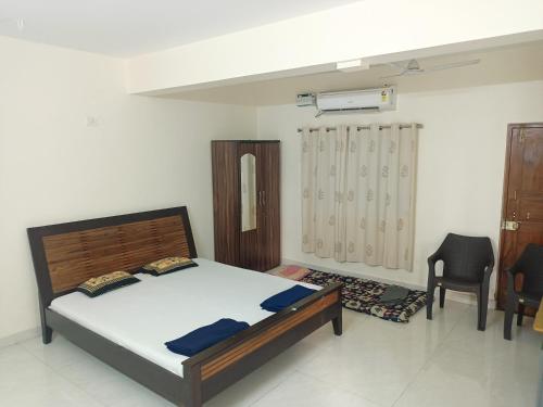 een slaapkamer met een bed en 2 stoelen bij Sai Leela Guest House in Dabolim