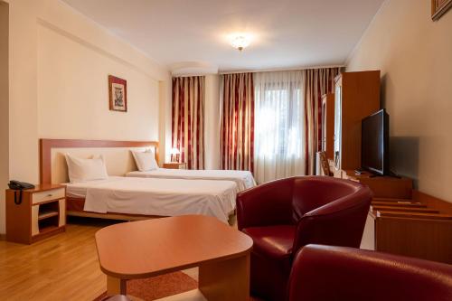 Habitación de hotel con cama y silla en Primavera 1 Hotel, en Pazardzhik