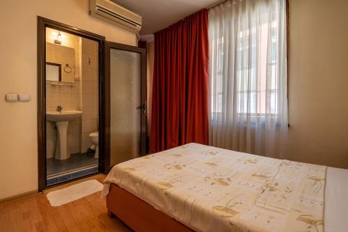 a bedroom with a bed and a bathroom with a window at Primavera 1 Hotel in Pazardzhik