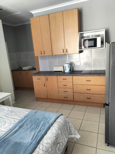 a kitchen with wooden cabinets and a black counter top at Gqeberha Self Catering Apartments in Kensington