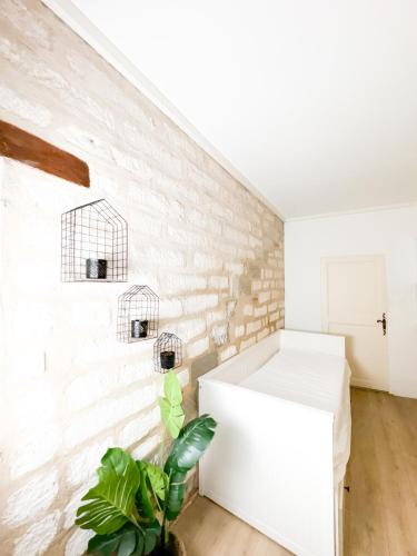 une chambre blanche avec un mur en briques et une plante dans l'établissement Balisier Studio avenue de Lodève, à Montpellier